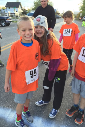 Kids in orange tshirts smiling before a race